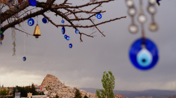 Hand holding an Evil Eye amulet, representing the alternate belief.