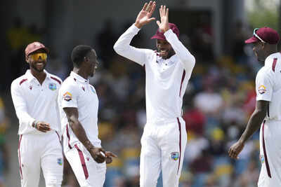Roston Chase congratulates Shamar Joseph after a successful day of bowling.